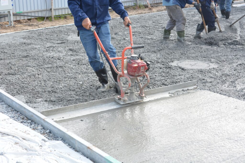 Workers leveling freshly placed concrete slab